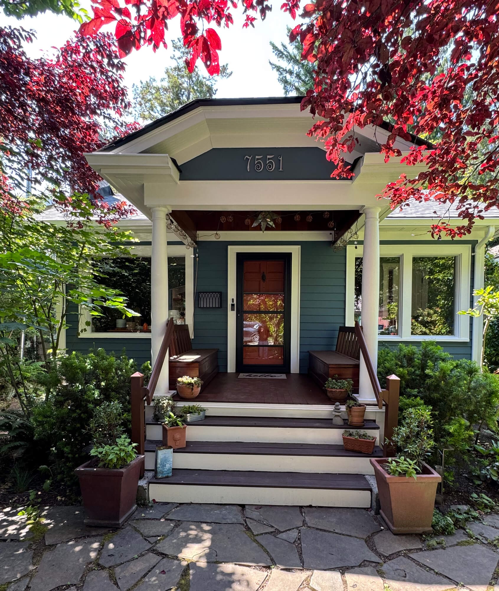 Freshly painted craftsman-style home exterior with a welcoming front porch, clean trim, and rich siding colours surrounded by landscaped greenery.